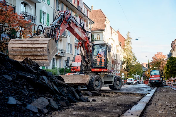 Excavator removing soil on a residential street in Bern – groundwork for unsealing and green infrastructure following the Sponge City approach.