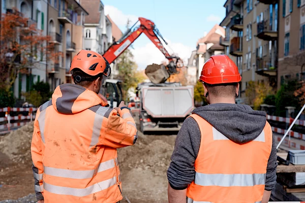 Two site supervisors observing excavation work in Bern – teamwork and coordination in road construction.